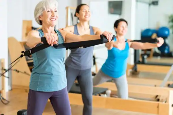 Toning Arms After 60: Empowering Womens Fitness Through Effective Weight Training 2 older woman doing weight training Essex and resistance in the gym to tone upper arms