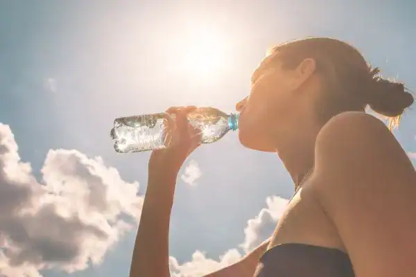 Hydration: The Secret Ingredient for a Toned Stomach and Enhanced Fitness 3 Image of woman drinking water to hydrate Essex after run.