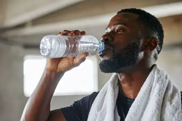 Hydration: The Secret Ingredient for a Toned Stomach and Enhanced Fitness 1 Image of man drinking water to improve hydration Essex after work out.